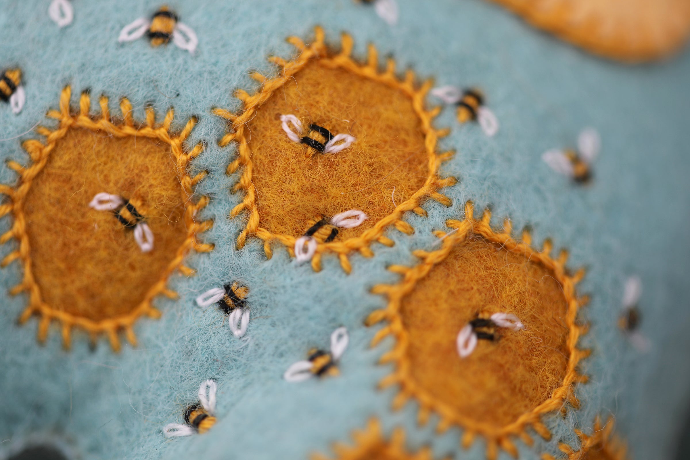 Close-up of embroidered bee designs on fabric with a blue background