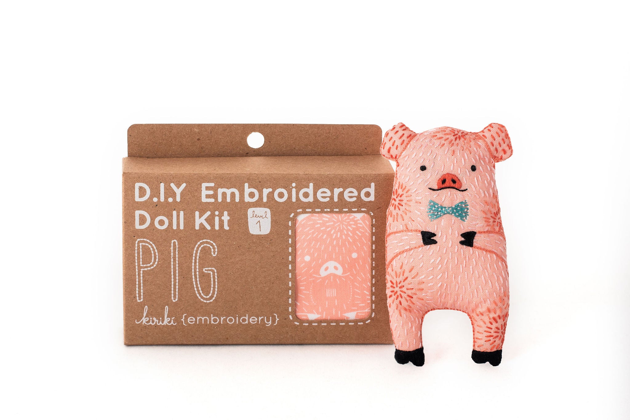 Pink pig embroidered doll kit with packaging on a white background