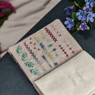 Embroidered fabric with stitch samples on a dark surface with flowers in the background