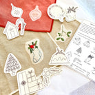 Set of Christmas-themed embroidered patterns on a fabric surface with a printed sheet of instructions.