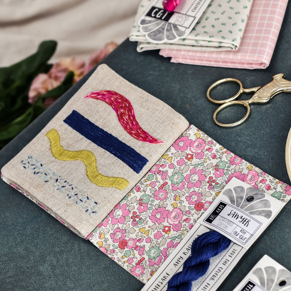 Embroidered fabric patch with floral patterns and embroidery threads on a table.