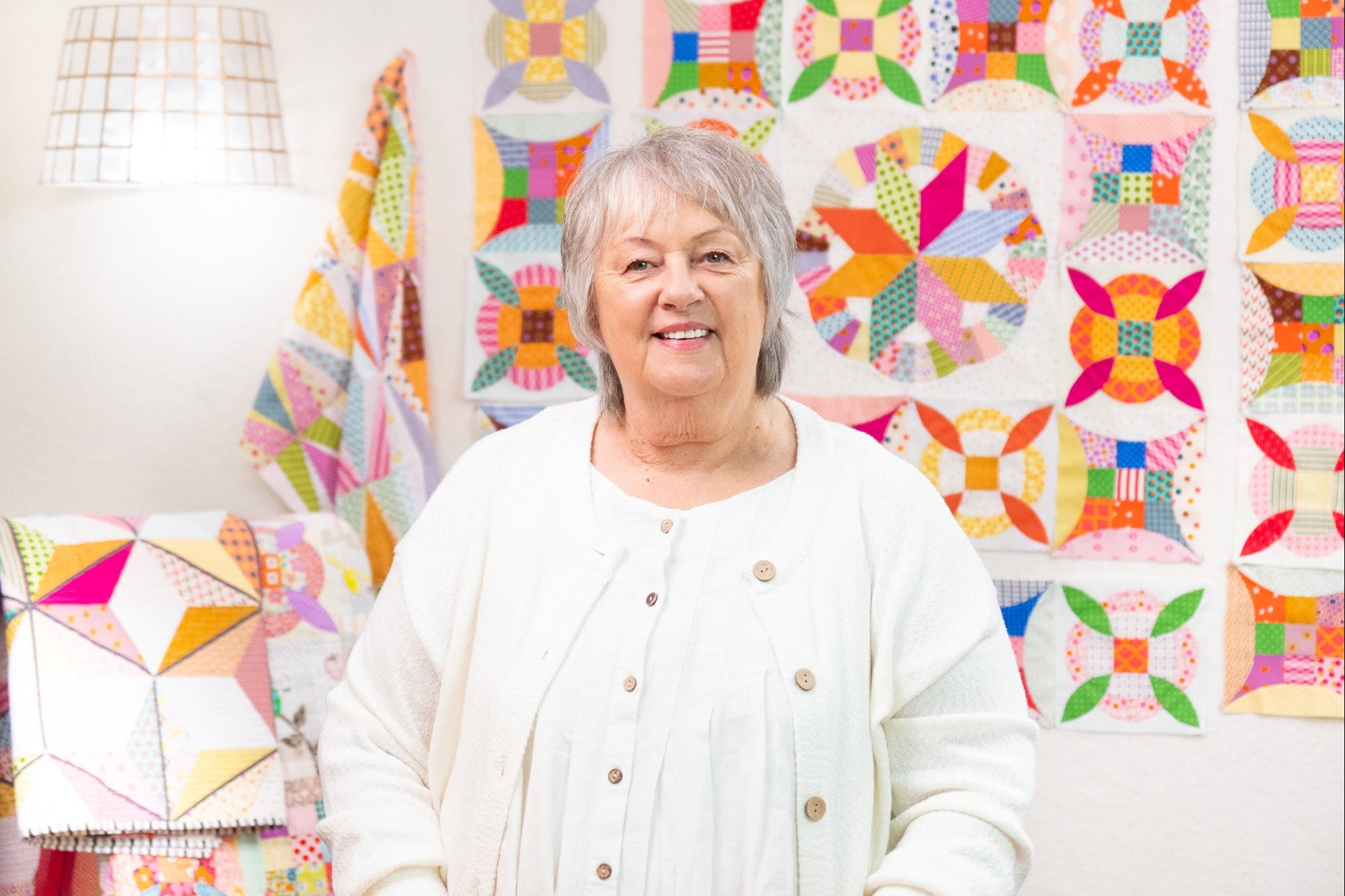 Woman standing in front of a colorful quilt display