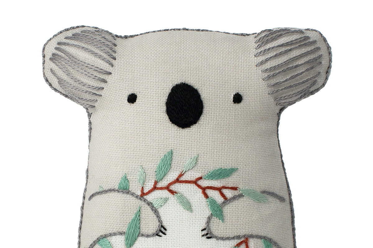 Stuffed koala toy with leaf design on a white background