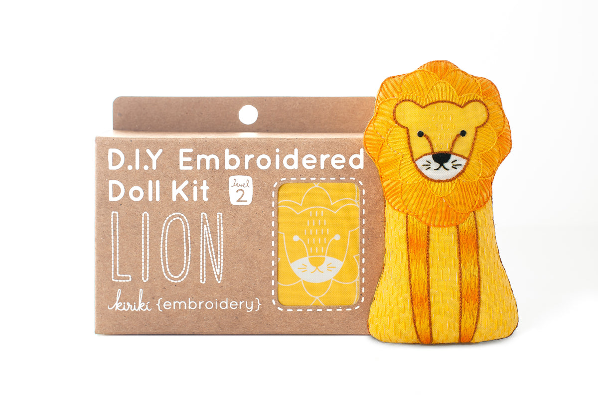Yellow lion toy with a DIY embroidered doll kit packaging on a white background