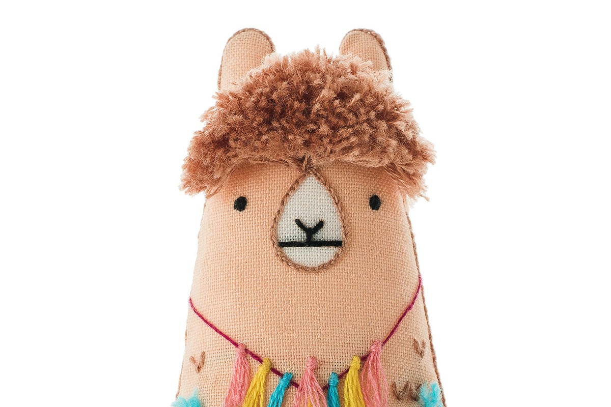 Stuffed toy llama with a fluffy brown top on a white background