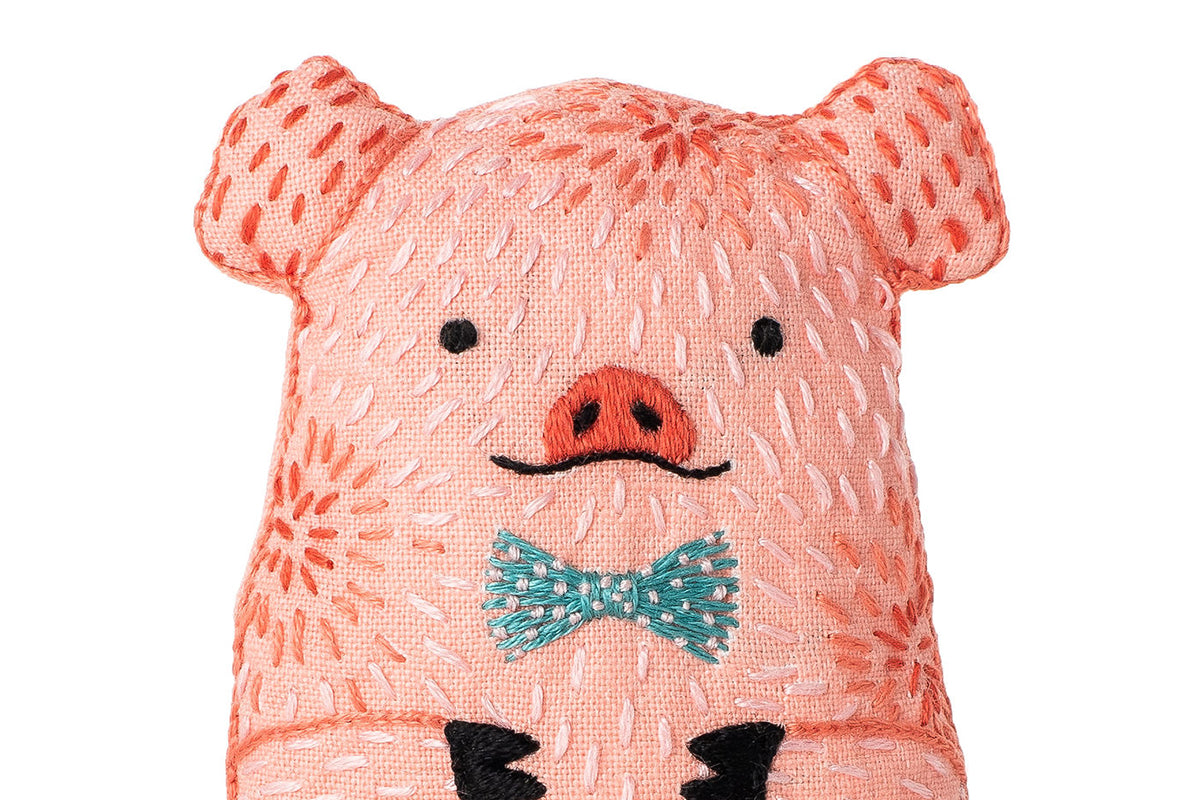 Pink pig plush toy with a bow tie on a white background