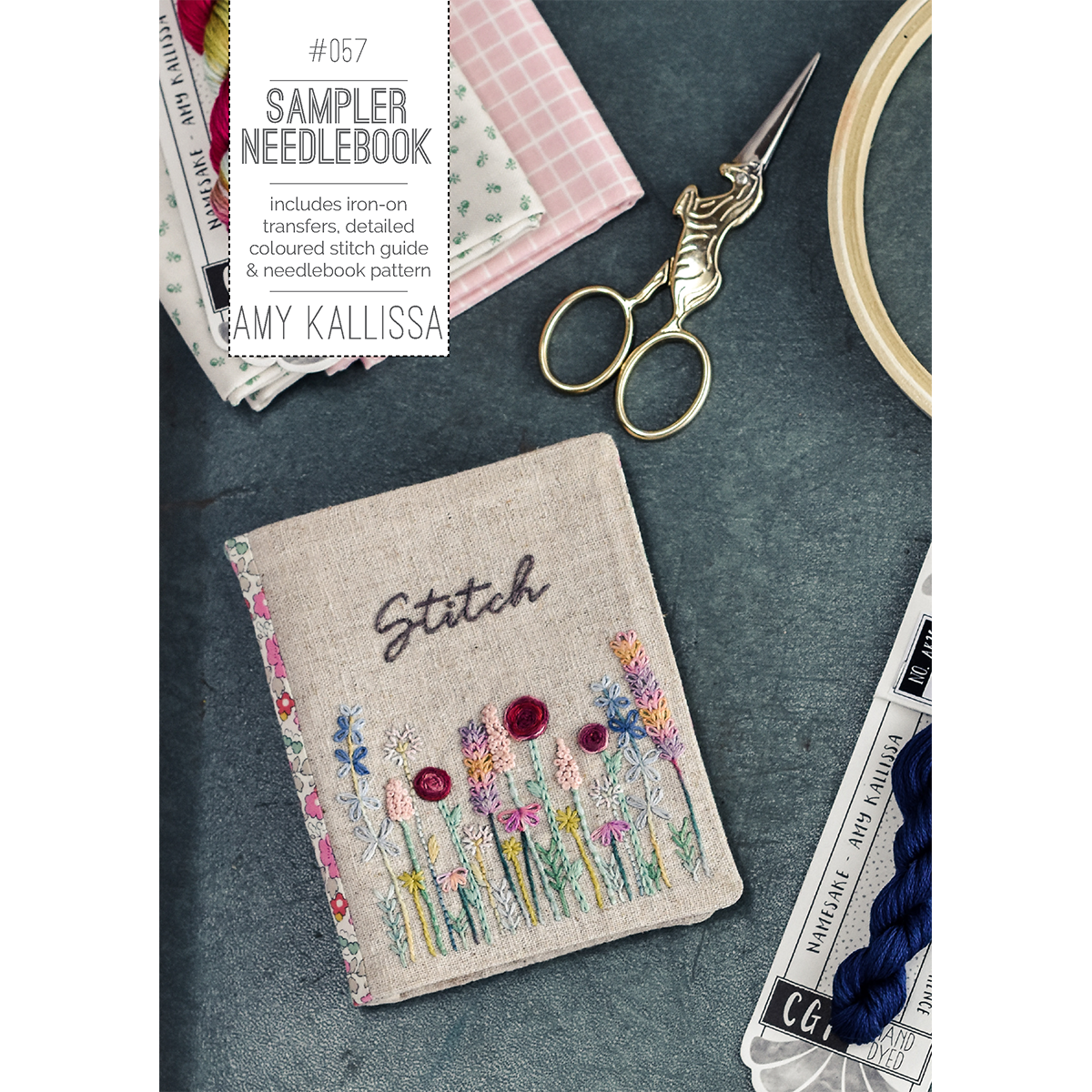 Sampler needlebook with floral embroidery design, scissors, and yarn on a dark surface