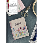 Sampler needlebook with floral embroidery design, scissors, and yarn on a dark surface